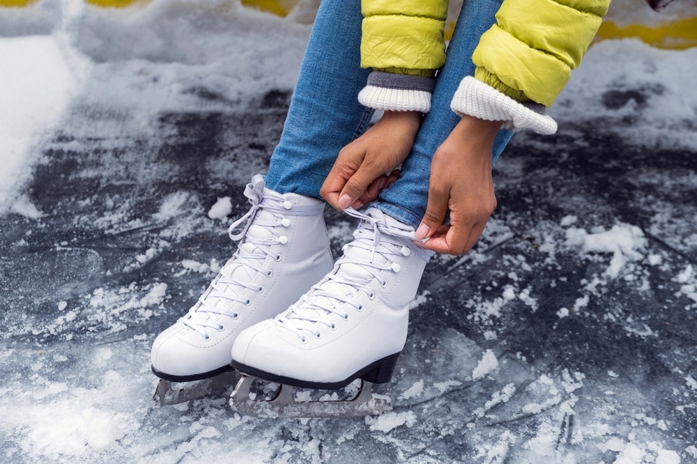 Discover the Cayuga Nature Center This Winter 2 Young woman putting ice skates on at outdoor rink near Cayuga Nature Center.